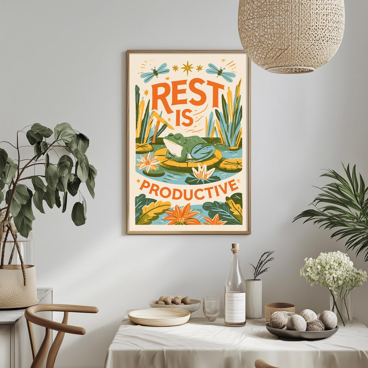 a framed poster with a vibrant illustration of a frog and flowers, hanging on a wall above a dining table with various decorative items and plants.