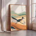 a large, framed poster depicting a bird in mid-flight against a desert landscape with mountains in the background.