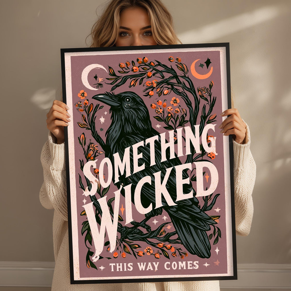 A woman holding a framed poster with a black bird and floral designs.