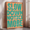 a large, colorful poster with the text "Slow down, notice more" displayed prominently in the center.