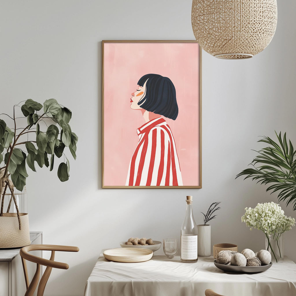 a dining table with a white tablecloth, a bowl of fruit, a bottle, and a vase with flowers. Above the table, there is a framed illustration of a woman with a red and white striped shirt.