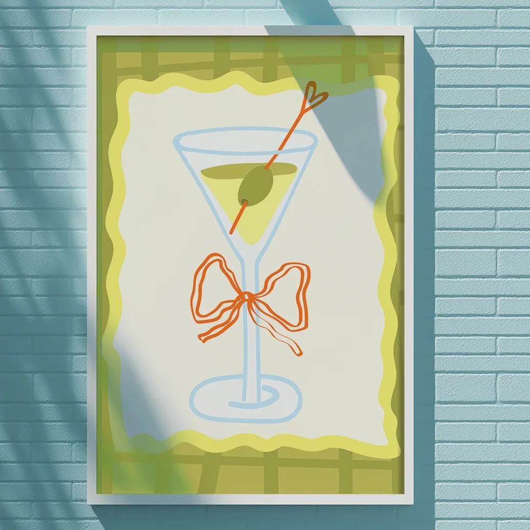 a framed picture of a martini glass with a bow on a blue brick wall.