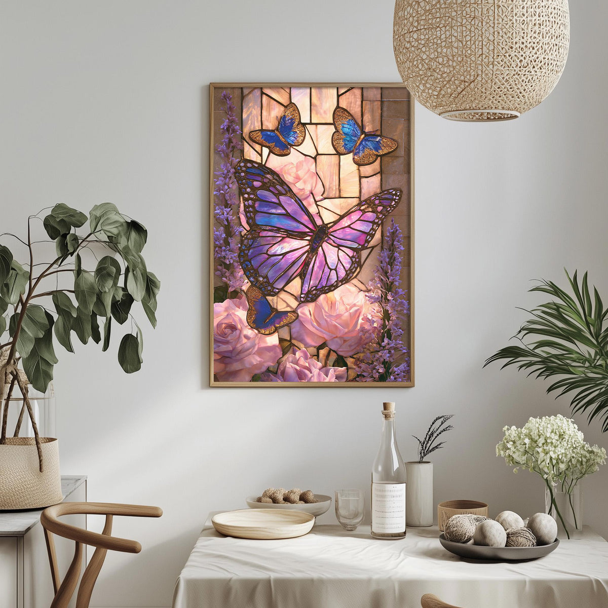 a dining table with a white tablecloth, a vase of white flowers, a bottle, and a bowl of fruit. Above the table, there is a framed painting of a butterfly surrounded by flowers and a stained glass window.