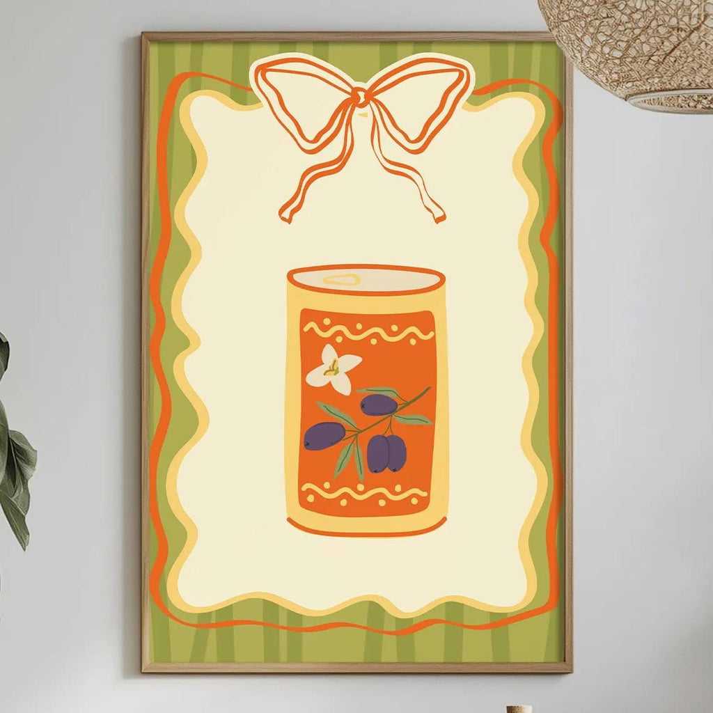 a dining table with a white tablecloth, a bowl of fruit, a bottle, and a vase with flowers. Above the table, there is a framed picture of a can with a bow on it.