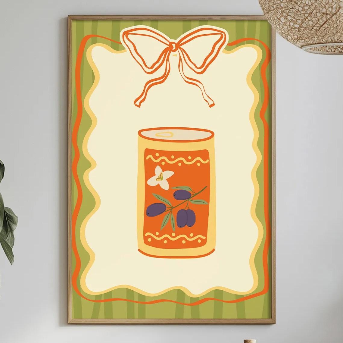 a dining table with a white tablecloth, a bowl of fruit, a bottle, and a vase with flowers. Above the table, there is a framed picture of a can with a bow on it.