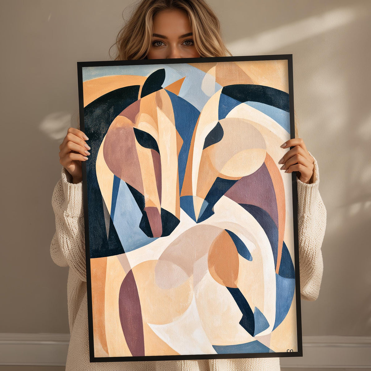 A woman is holding up a framed abstract painting of two stylized horses.