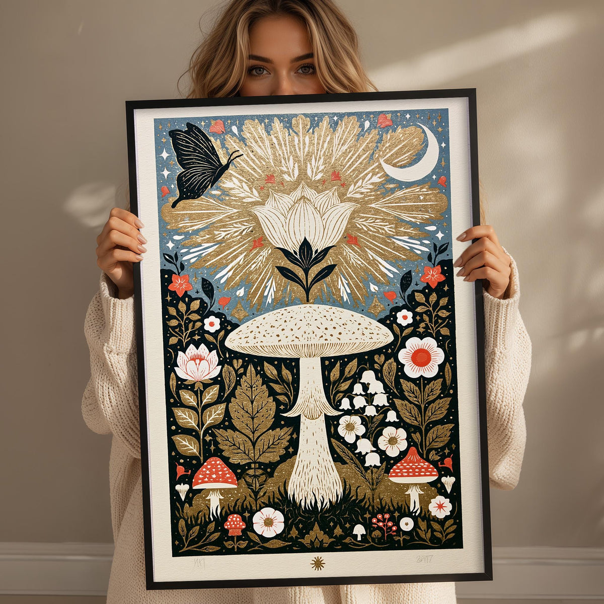 A woman is holding up a framed artwork featuring a vibrant, colorful illustration of a flower, mushrooms, and other natural elements.