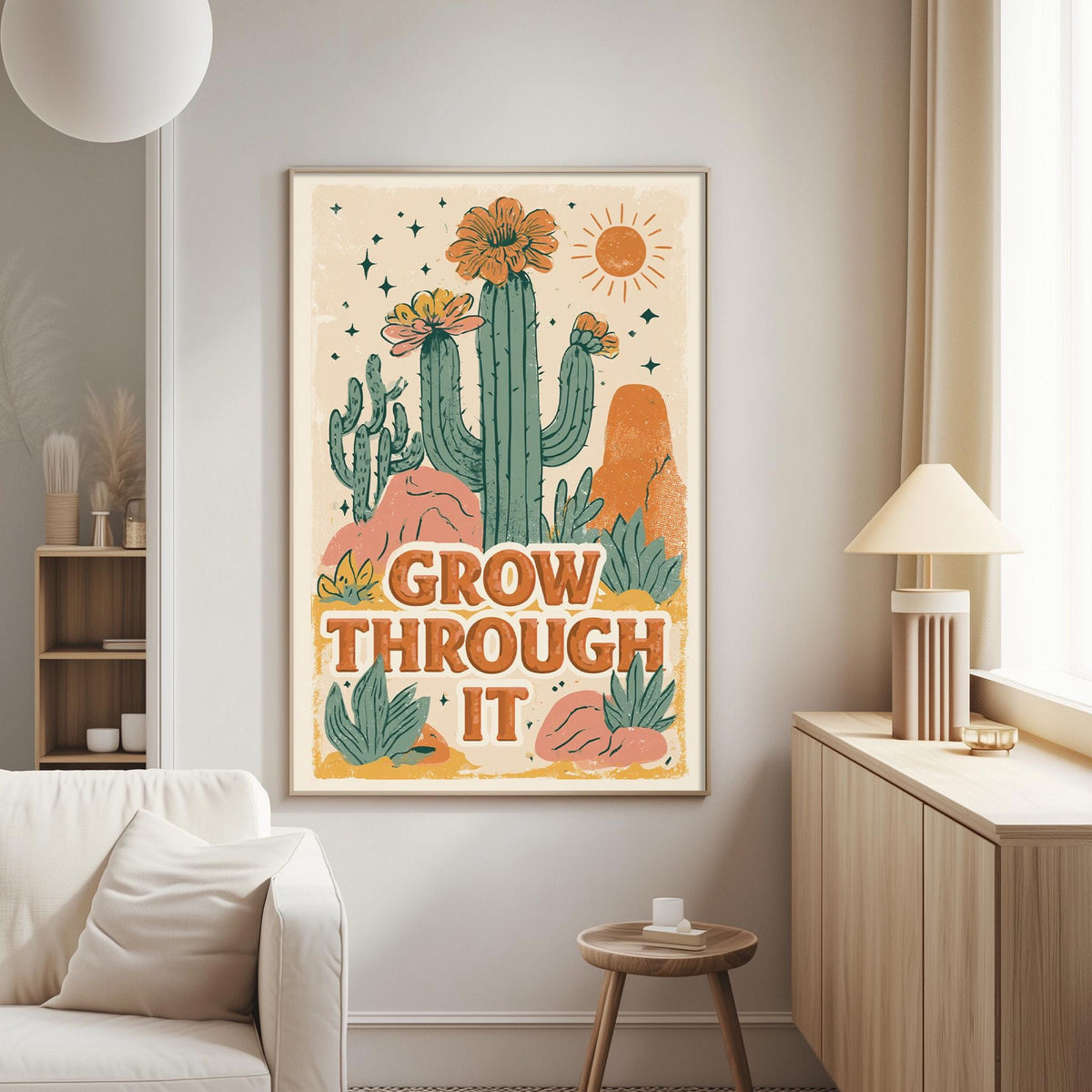 a poster with a desert-themed illustration and the text "GROW THROUGH IT" displayed on a wall in a living room setting.