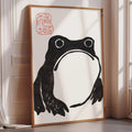 a large framed artwork depicting a black frog with a red stamp on the top left corner.