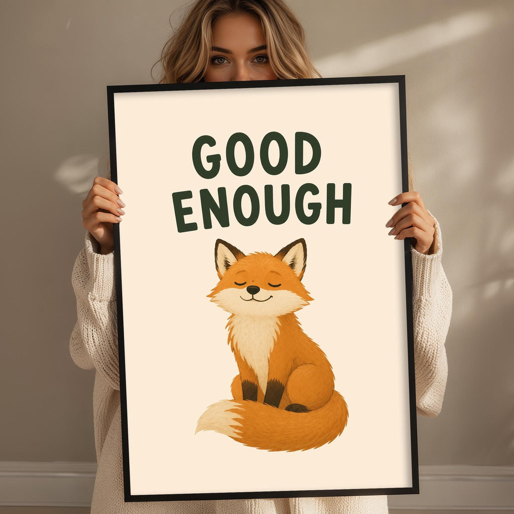 A woman holding a framed poster with a cartoon image of a fox and the text "GOOD ENOUGH" written above it.