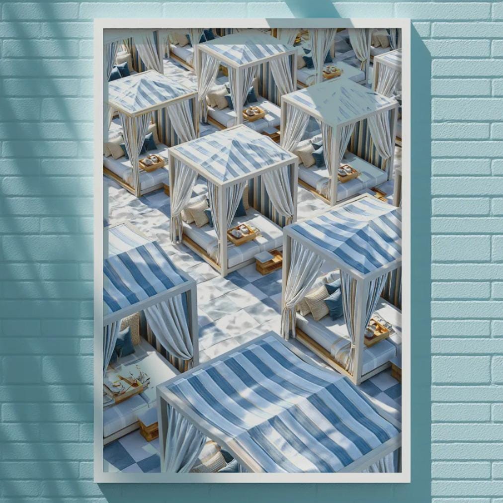 a blue wall with a framed photograph of a beach scene, including beach chairs and umbrellas.