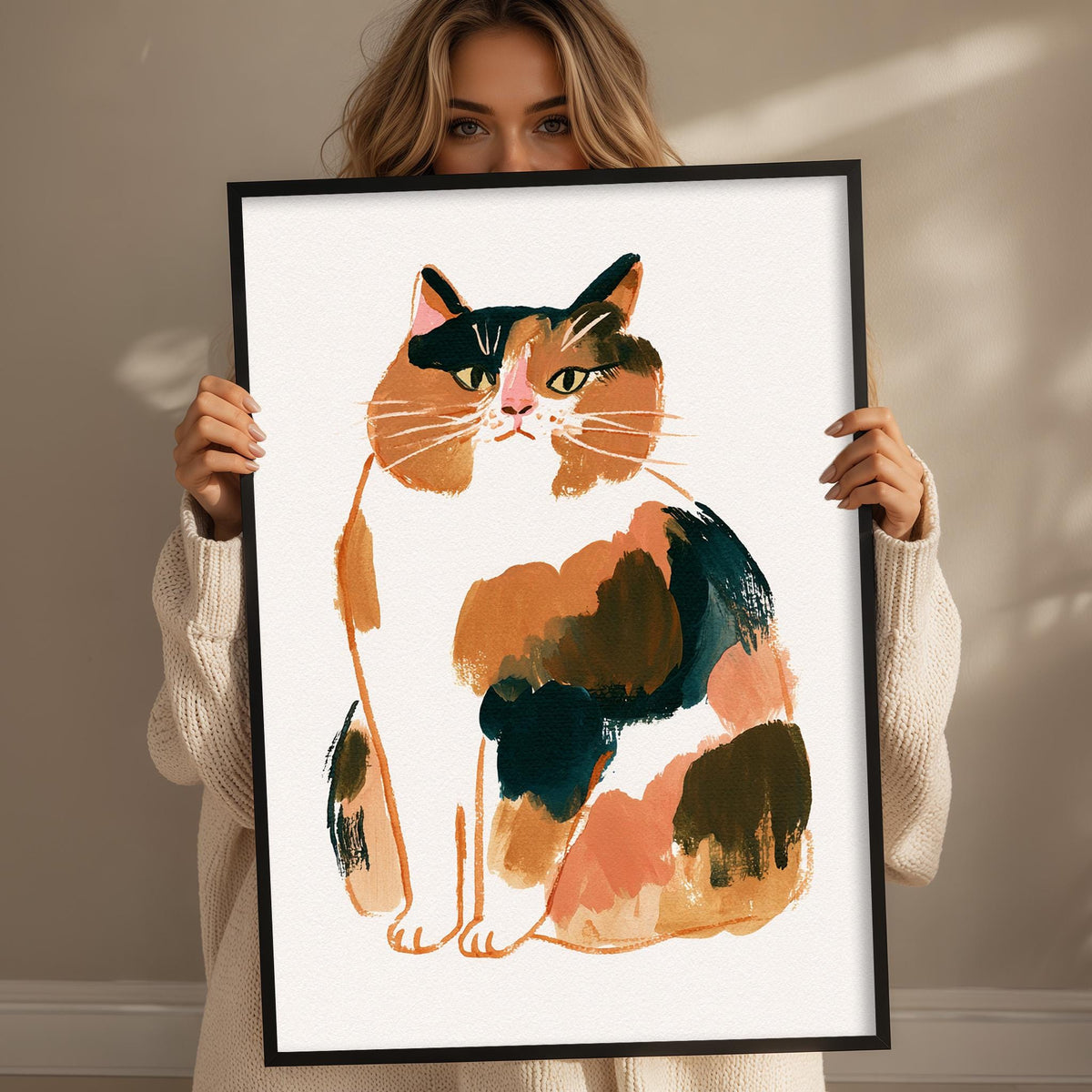 A woman is holding up a framed illustration of a cat, which appears to be a colorful and detailed depiction of the animal.