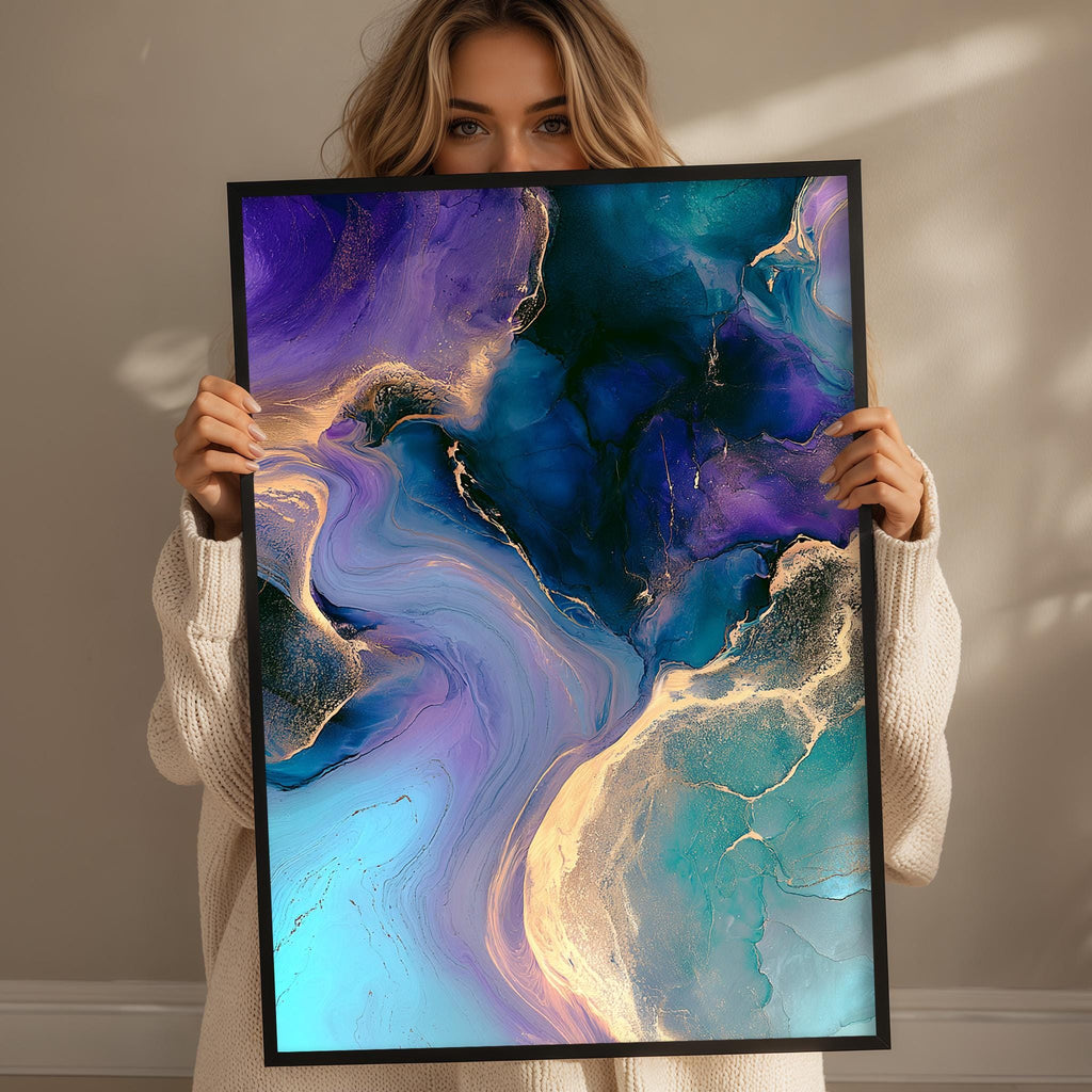 A woman holds up a framed abstract painting with a vibrant mix of blue, purple, and gold colors, creating a visually striking and dynamic composition.