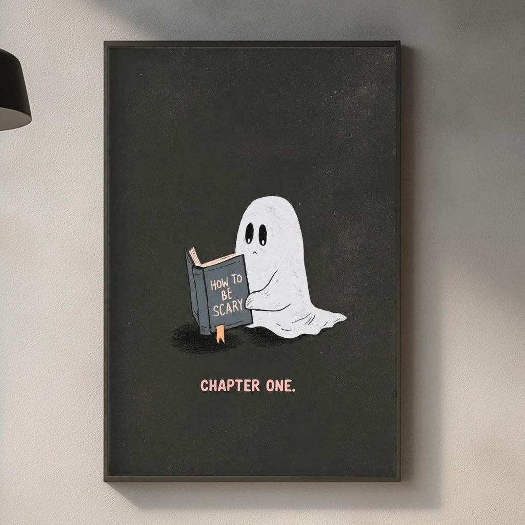 a kitchen counter with various items, including a plant, a cutting board, and a sink. Above the counter, there is a framed illustration of a ghost holding a book and the text "How to be a scary ghost" written on it.