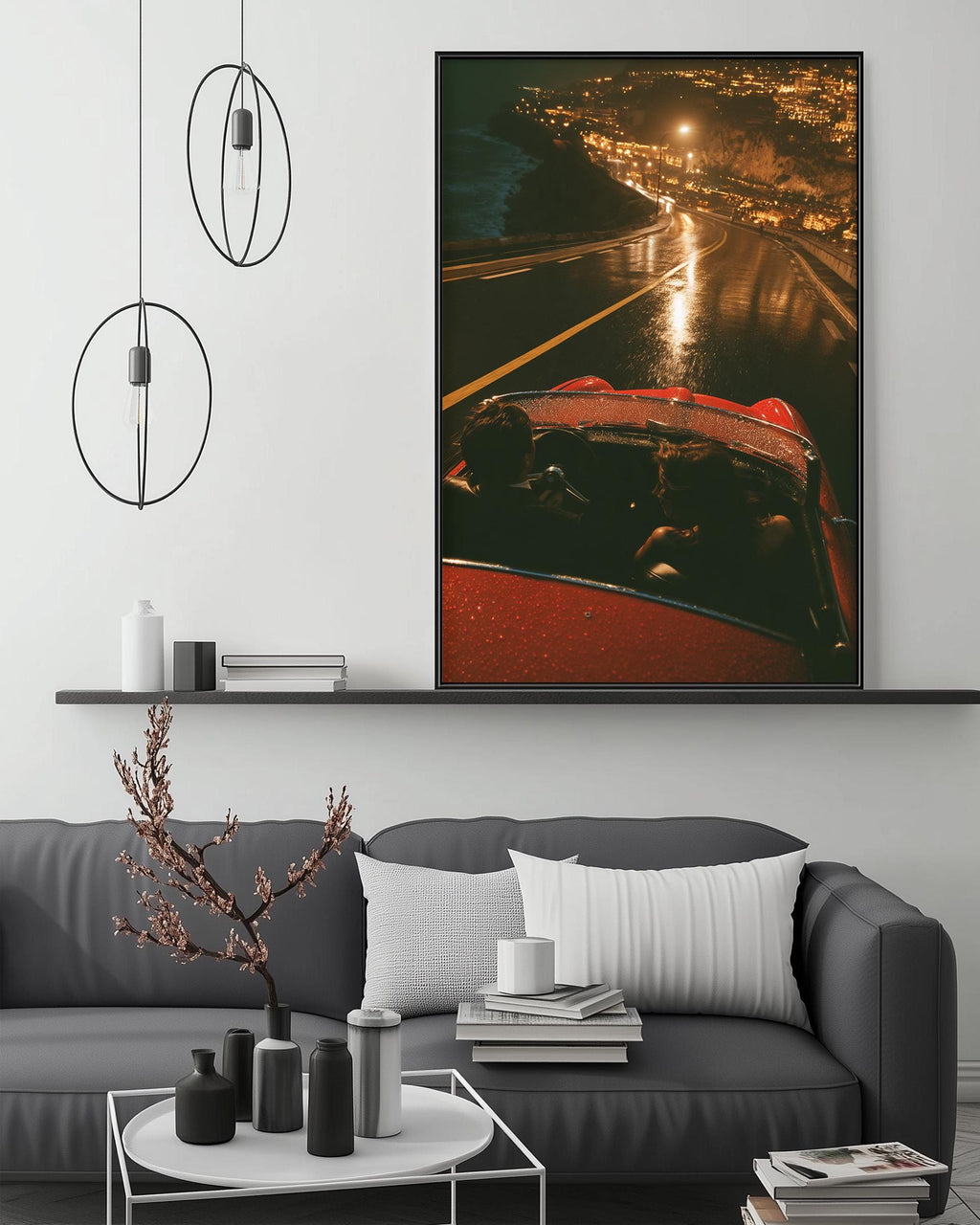 a modern living room with a gray sofa, a coffee table, and a large framed photograph of a red car driving down a road at night. The photograph captures the car's headlights illuminating the road and the surrounding area, creating a warm and inviting atmosphere.