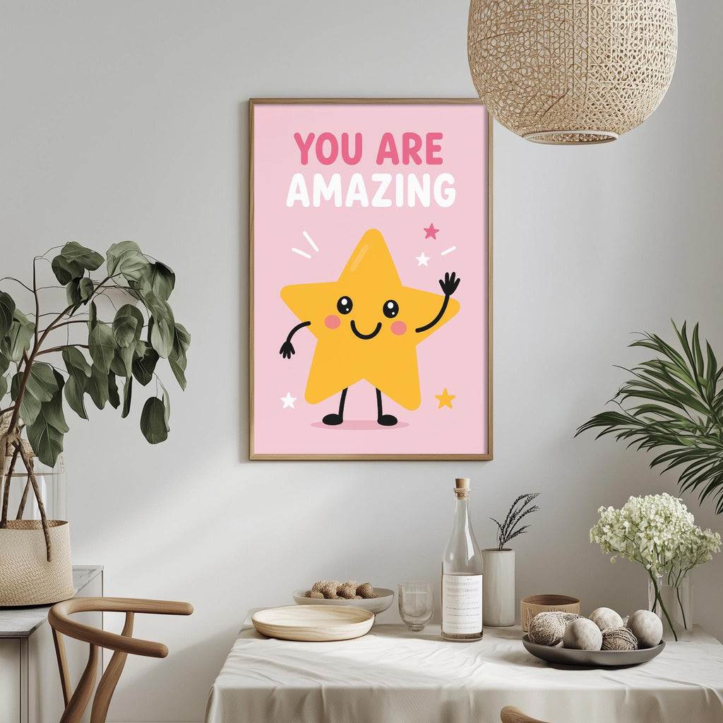 a framed poster with a cheerful yellow star character on a pink background, surrounded by stars and flowers, with the text "YOU ARE AMAZING" displayed above the star. The poster is hung on a wall above a dining table with various items on it, including a bottle, a bowl, and a vase.
