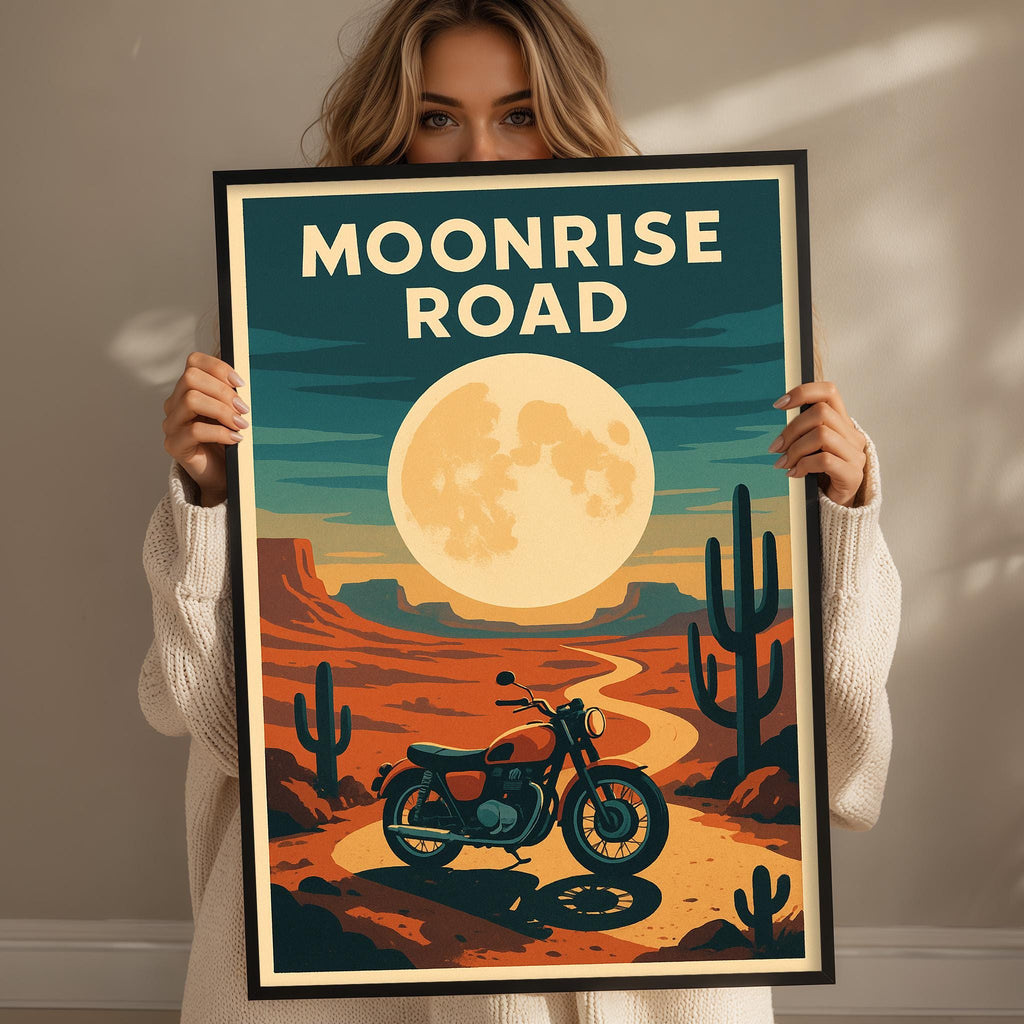 A woman holds up a framed poster depicting a desert landscape with a cactus, a motorcycle, and a large moon in the sky.