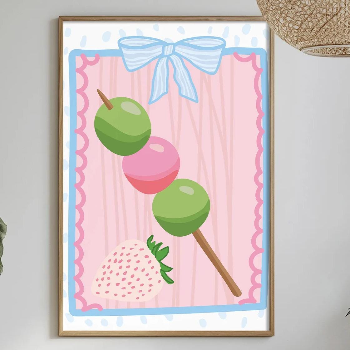 a dining table with a white tablecloth, a bowl of fruit, a bottle, and a vase with flowers. A framed picture of a strawberry and green olives is hanging on the wall above the table.