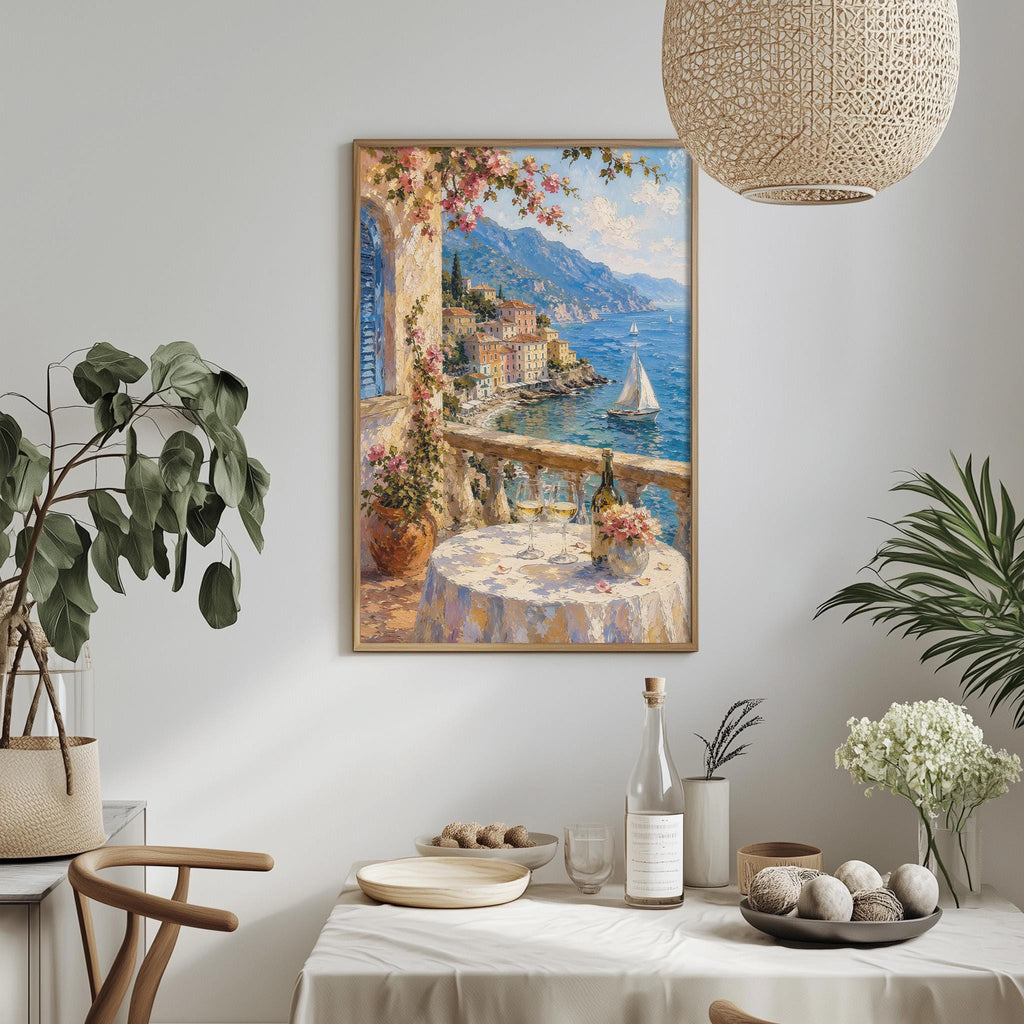 a dining table with a white tablecloth, a vase of flowers, a bottle of wine, and a bowl of fruit. Above the table, there is a framed painting depicting a scenic view of a coastal town with a sailboat on the water.