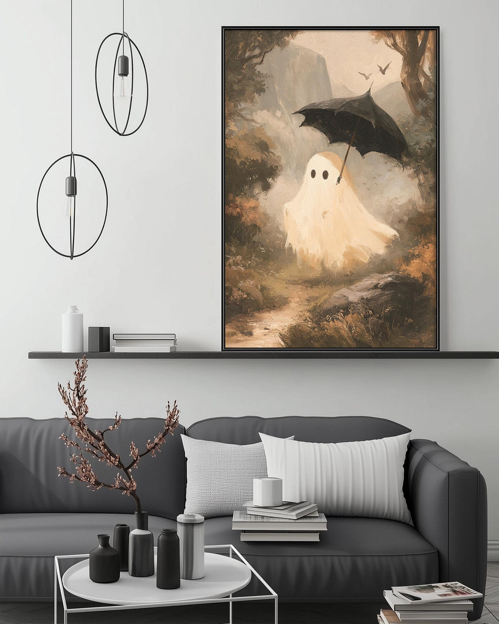 a large painting of a ghost-like figure holding an umbrella, set against a forest landscape. The painting is displayed on a wall above a gray couch, which has a coffee table in front of it. The room has a minimalist and modern design, with pendant lights hanging from the ceiling and a bookshelf filled with various items.