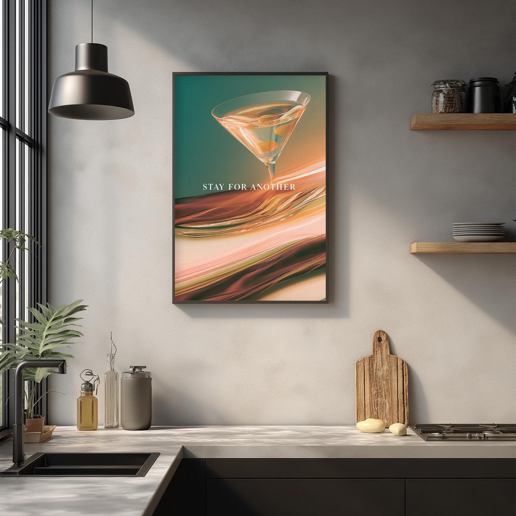 a kitchen counter with various items such as a cutting board, a bottle, and a plant. Above the counter, there is a framed poster with a cocktail glass and the text "STAY FOR ANOTHER" displayed on it.