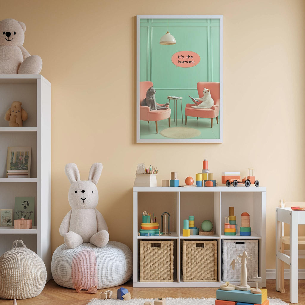 A child's bedroom with a white bookshelf, a stuffed rabbit, a toy chair, and a colorful toy set. Above the bookshelf is a framed poster with a cartoon cat and the text "It's the humans".