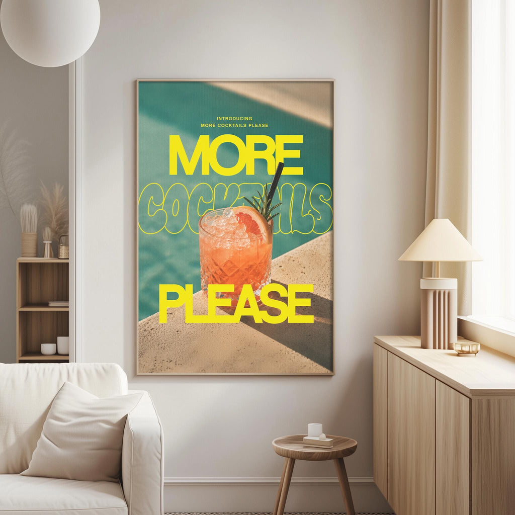 a poster with a large text that says "MORE COCKTAILS PLEASE" and an illustration of a cocktail. The poster is displayed on a wall in a living room setting, with a white couch and a small table nearby.