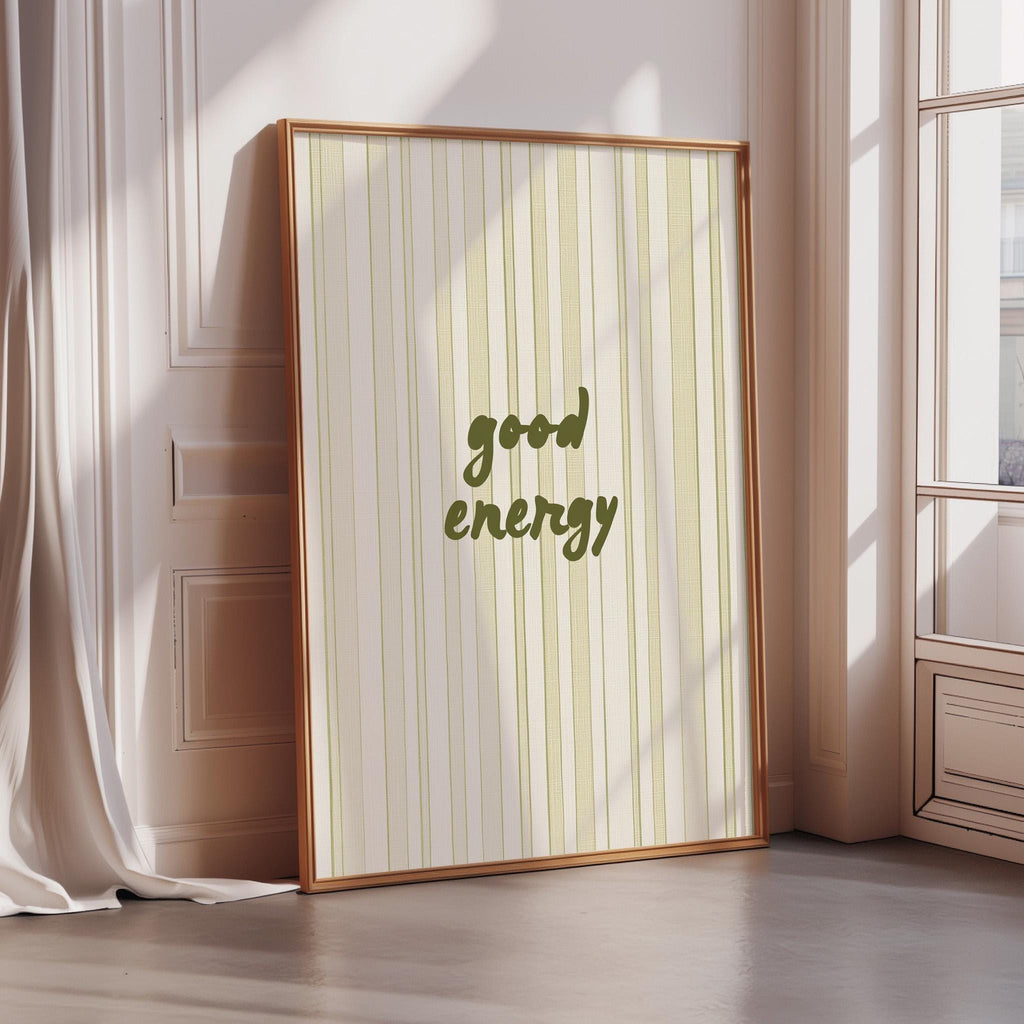 A framed poster with the text "good energy" is displayed on a wall in a room with a window.
