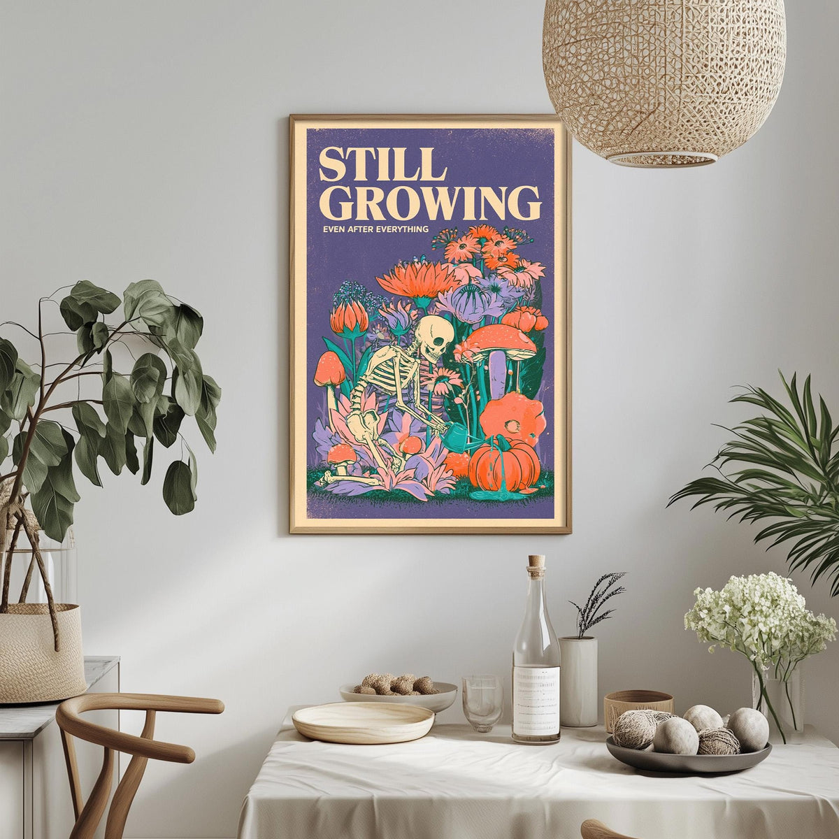 a framed poster with a skeleton and colorful flowers hanging on a wall above a dining table with various items on it.