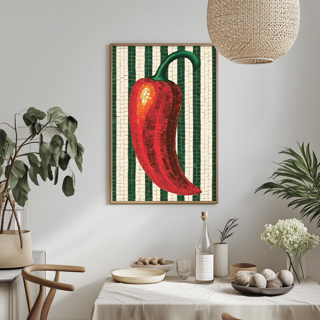 a dining table with a white tablecloth, a bowl of fruit, a bottle, and a vase with flowers. Above the table, there is a framed picture of a red pepper on a green and white striped background.