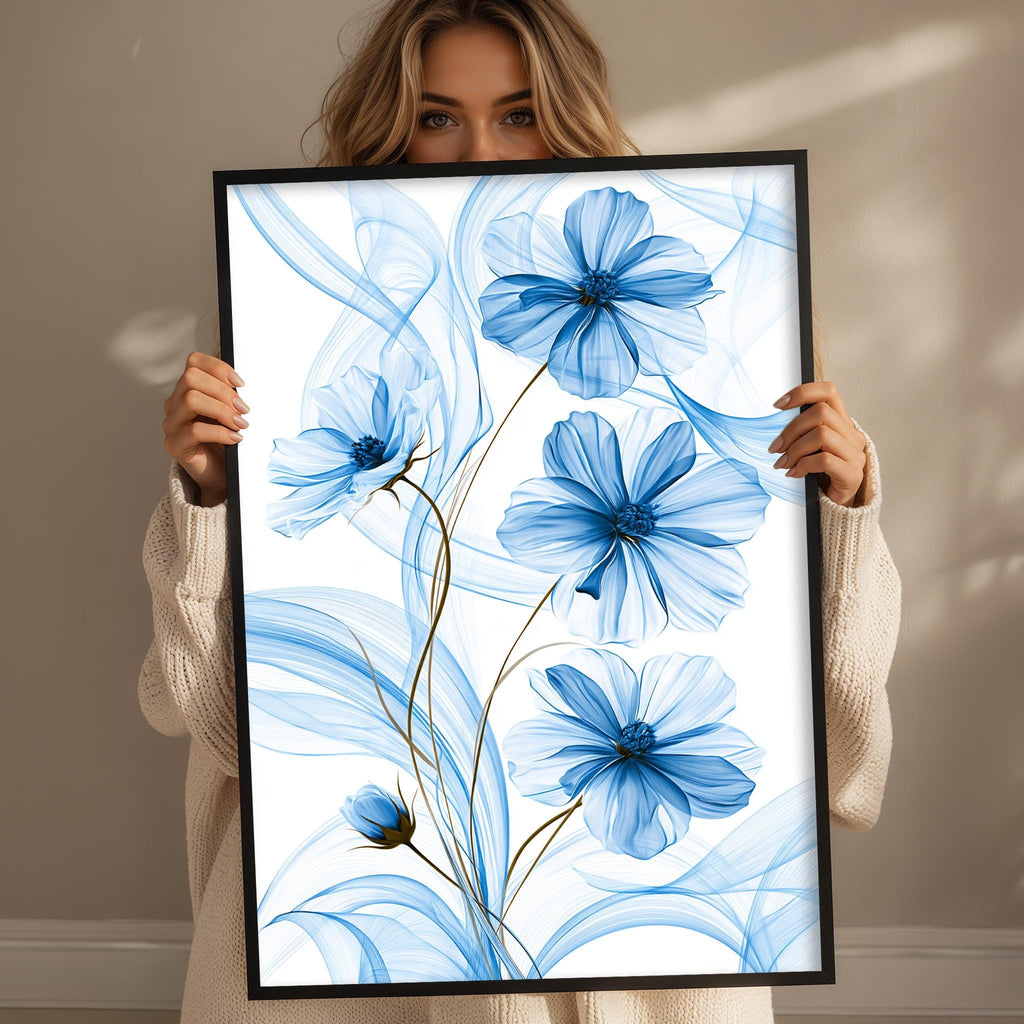 A woman is holding up a framed print with a blue floral design featuring white and blue flowers.