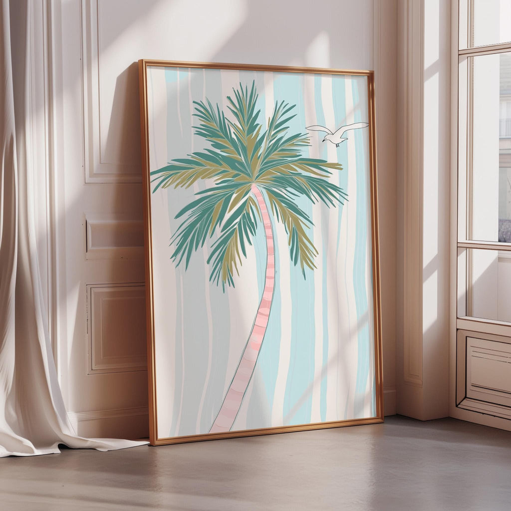 A framed poster of a palm tree with a bird in flight is displayed on a wall in a room with a window.