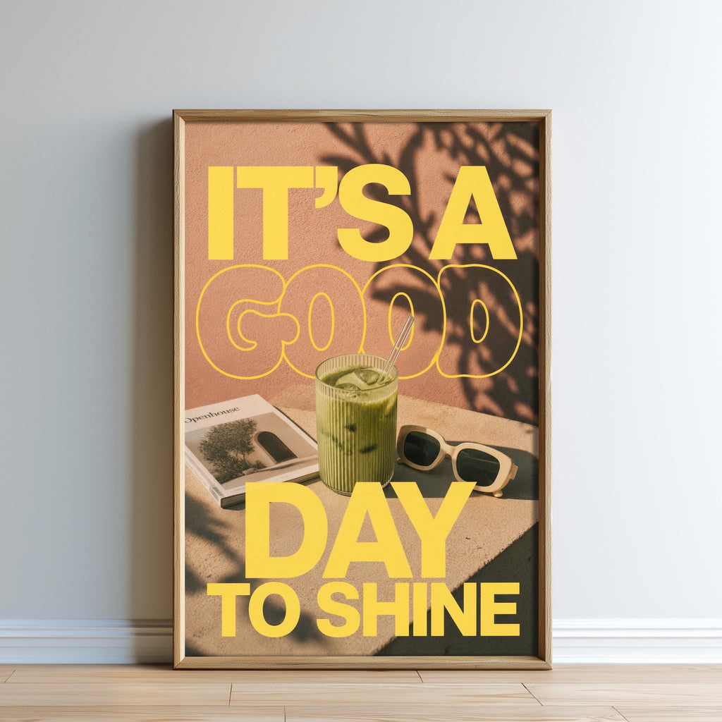 A framed poster with the text "IT'S A GOOD DAY TO SHINE" and an image of a green drink, sunglasses, and a magazine.