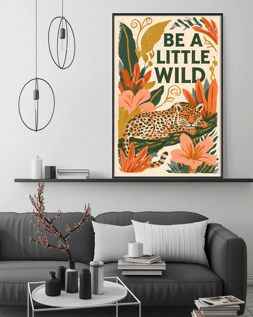 a living room with a gray couch, a coffee table, and a framed poster of a leopard resting on a leaf-filled background. The poster has the text "Be a little wild" written on it.