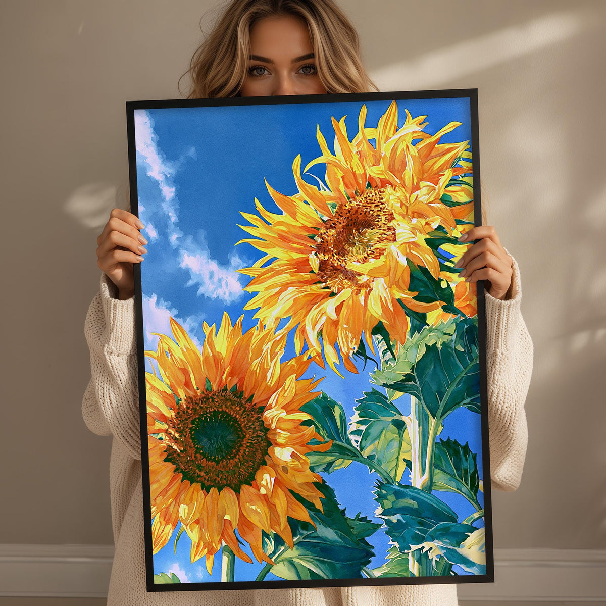 A woman holds up a framed painting of two vibrant sunflowers against a blue sky.