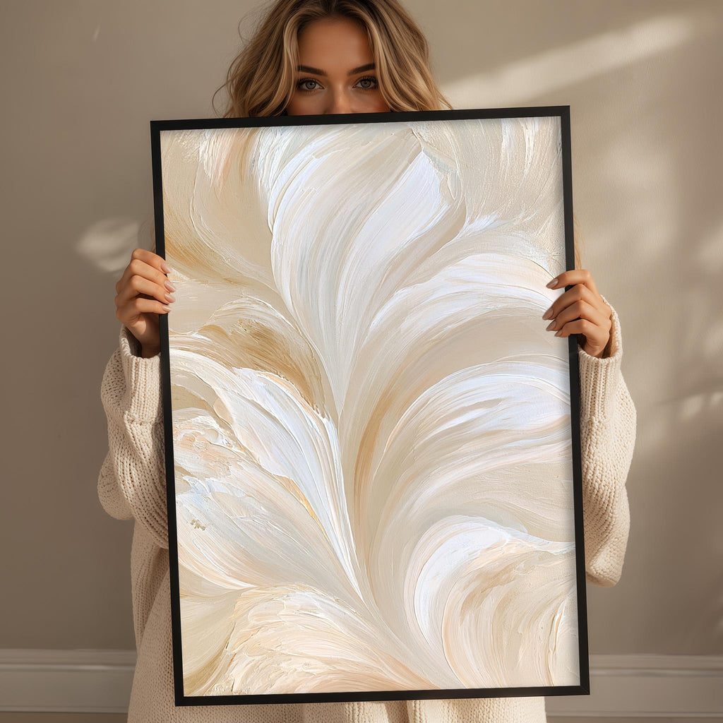 A woman holding a framed print with a large abstract painting of white and beige swirls and lines.