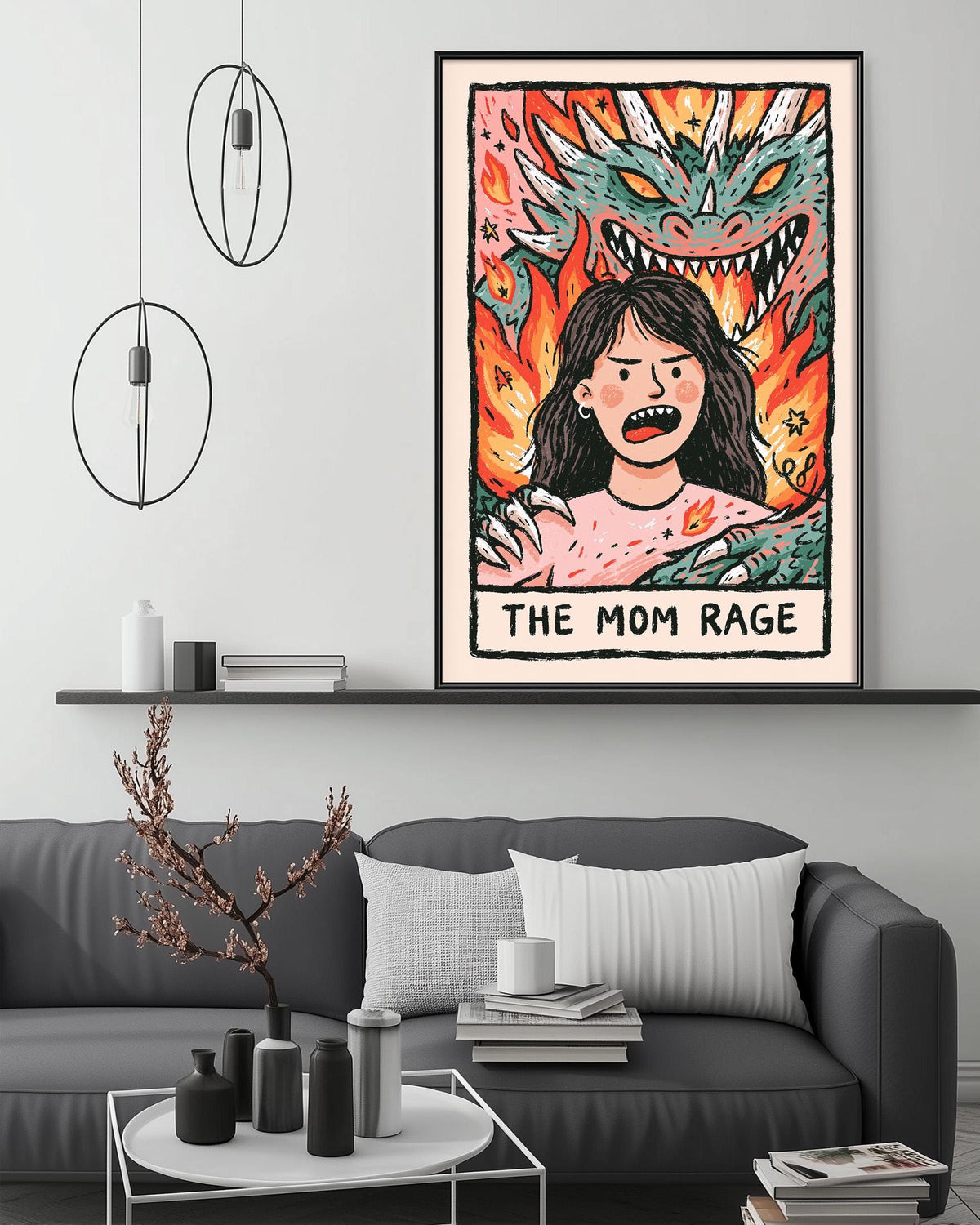 a poster of a woman with a dragon on her back, hanging on a wall above a gray couch with a coffee table in front of it.