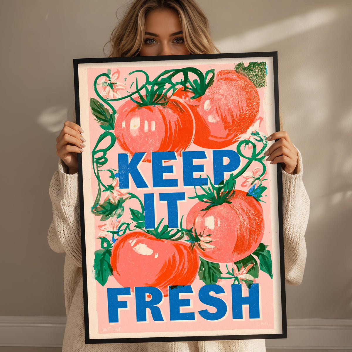 A woman holding a framed poster with a large graphic of tomatoes and the text "KEEP IT FRESH" written on it.