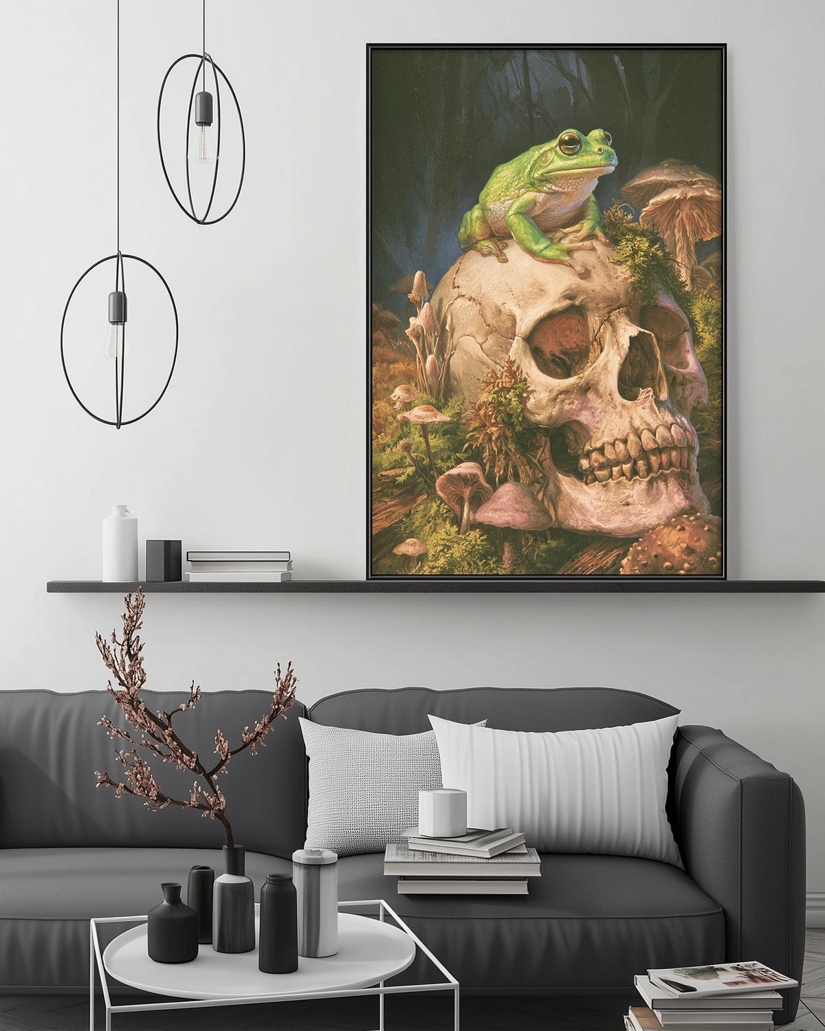 a large framed painting of a frog sitting on a skull, surrounded by mushrooms and plants, hanging on a wall above a gray couch in a living room setting.