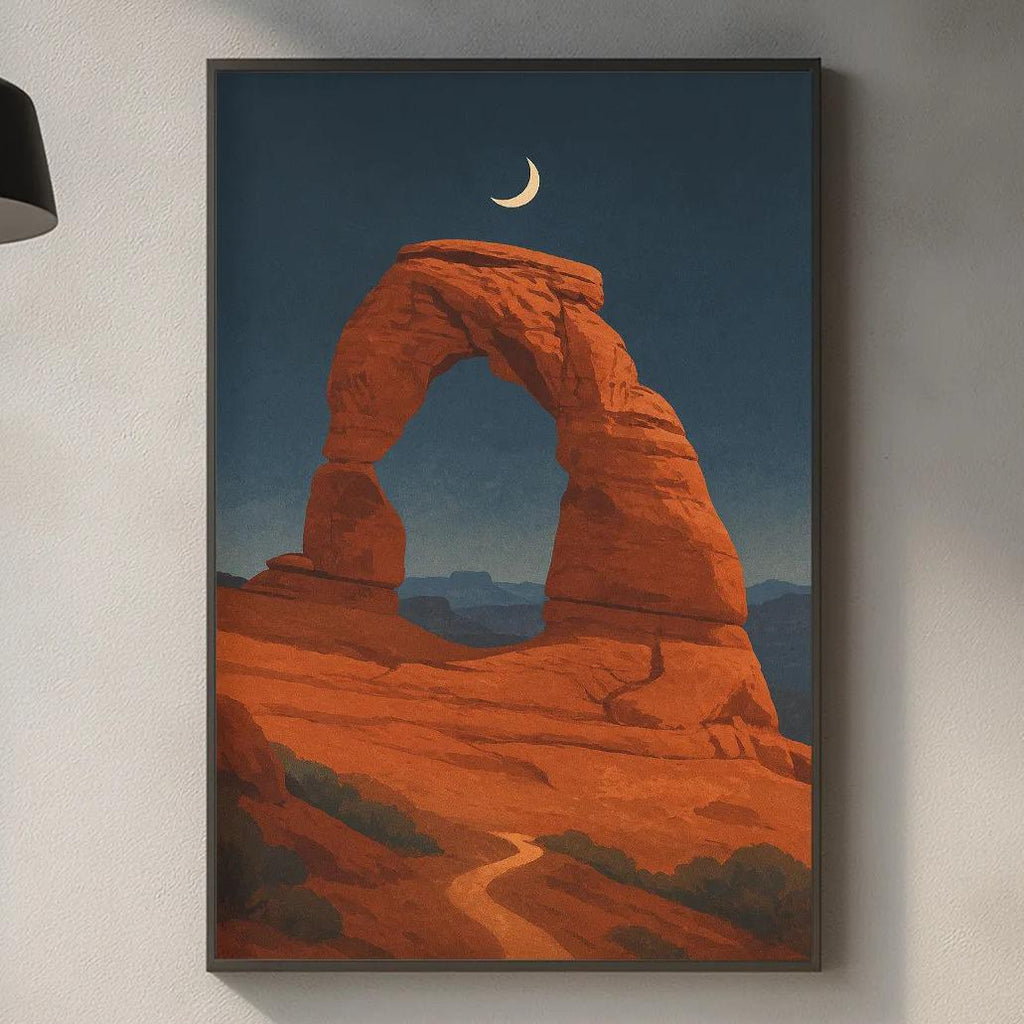 a kitchen counter with a framed painting of a desert landscape hanging above it. The painting depicts a large arch formation in the desert, with a crescent moon visible in the sky. The kitchen counter has various items on it, including a cutting board, a bottle, and a vase.